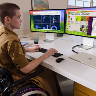 Člověk pracující na dvou externích displejích připojených k zavřenému hvězdně bílému 15palcovému MacBooku Air