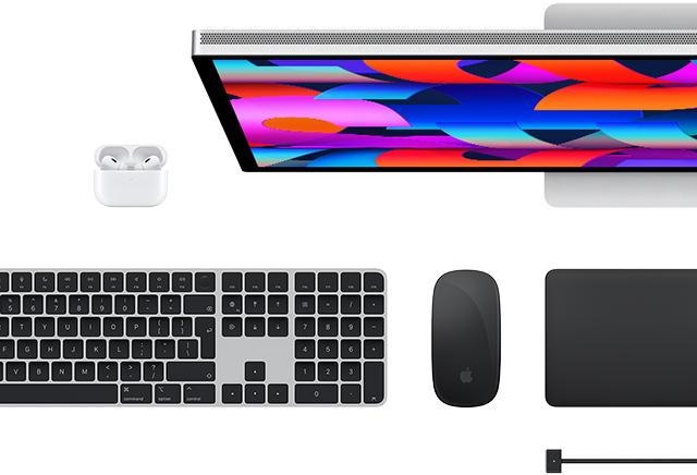 Pohled shora na doplňky k Macu: Studio Display, AirPods, Magic Keyboard, Magic Mouse a Magic Trackpad